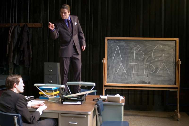 a man standing on a desk in front of a chalkboard