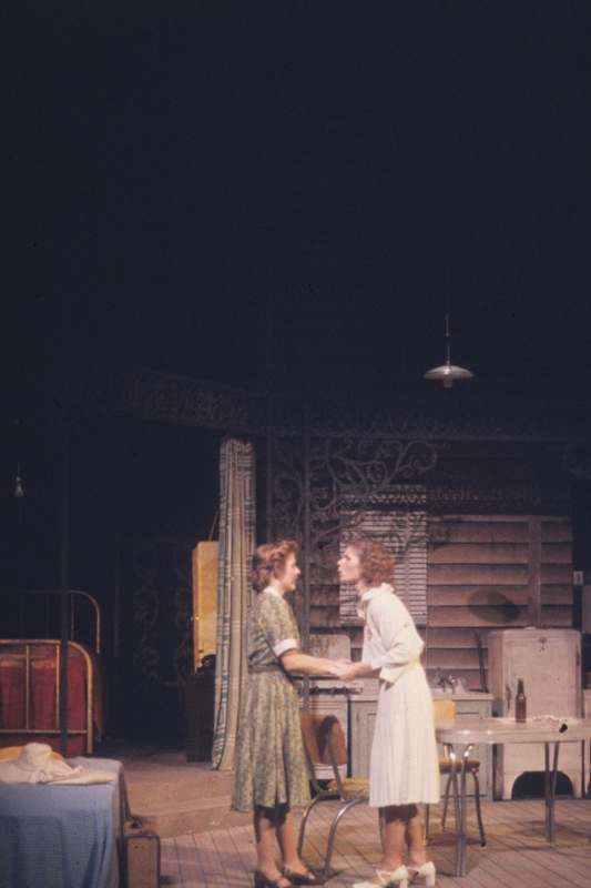 two women holding hands on a stage