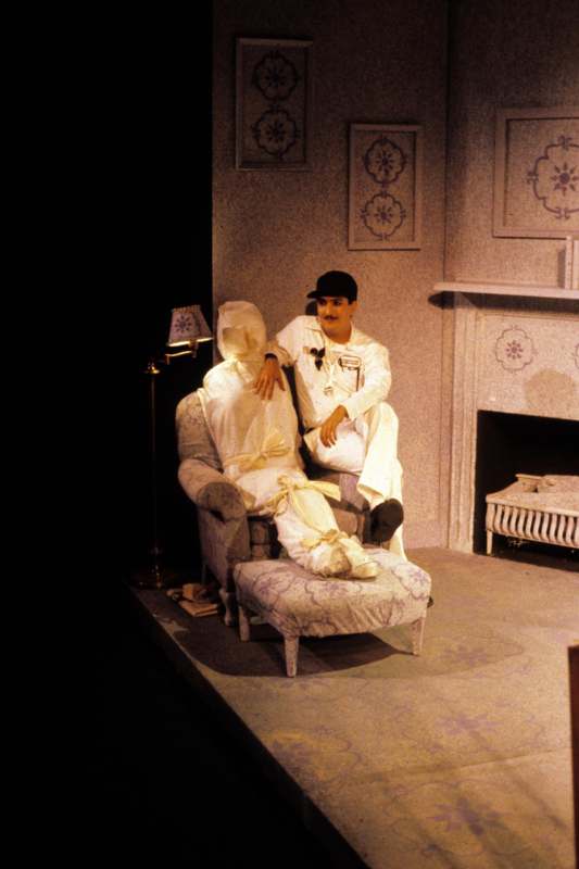 a man sitting on a chair with a person in white outfit