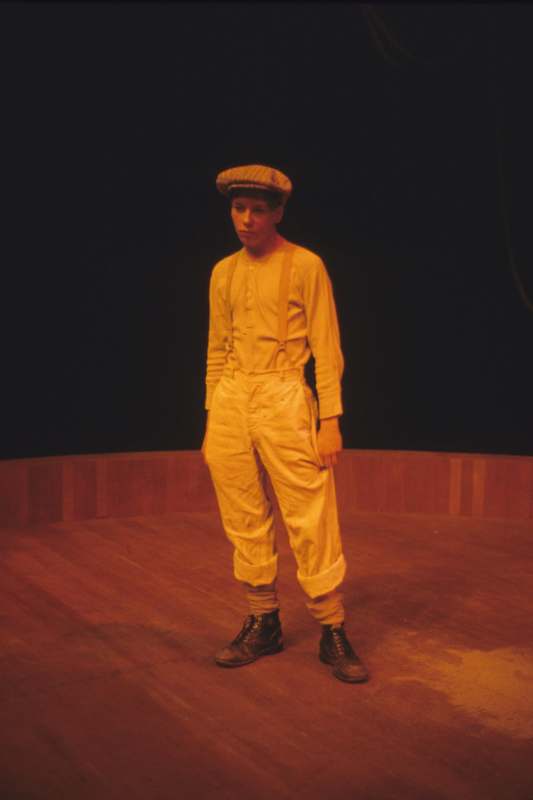a man in a hat and suspenders standing on a stage