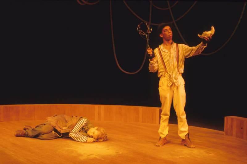 a man holding a whip and lying on a stage