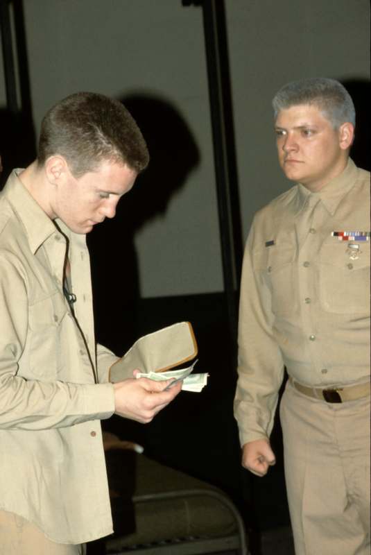 a man in uniform looking at a wallet with money