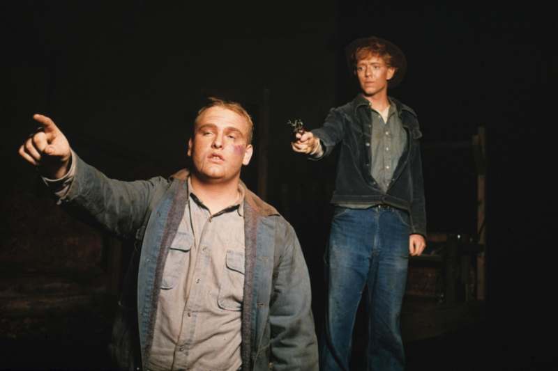 two men holding guns in a dark room