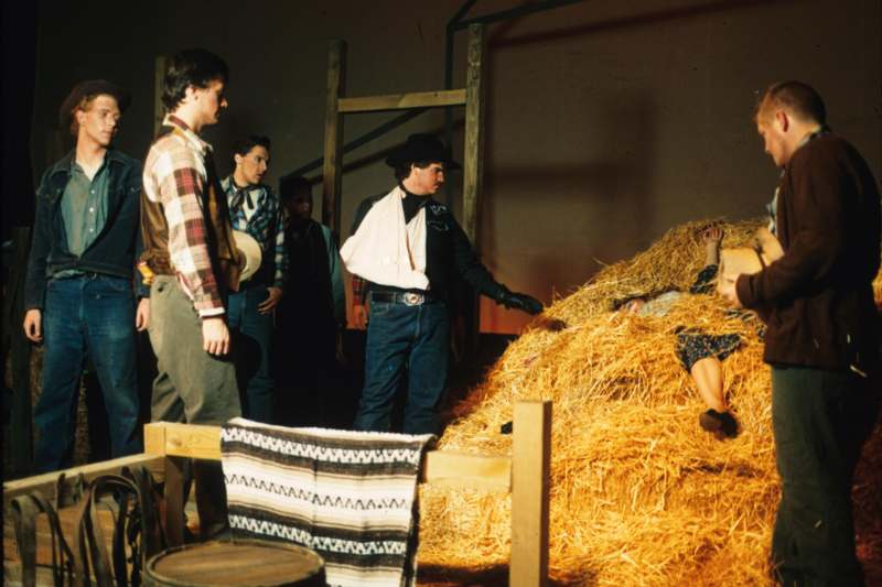 a group of people standing around a pile of hay