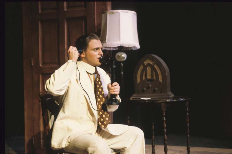 a man in a white suit holding a telephone
