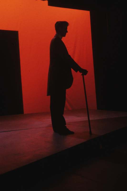 a man standing on a stage with a cane