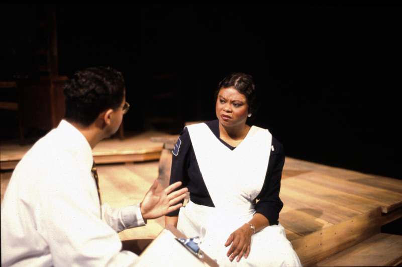 a woman sitting on a wooden platform talking to a man