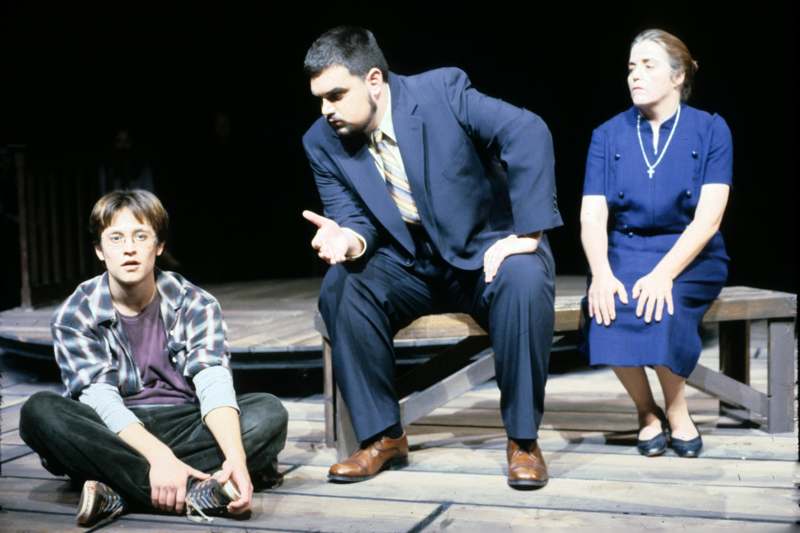 a man in a suit sitting on a bench with a man in a blue dress and a woman in a blue dress