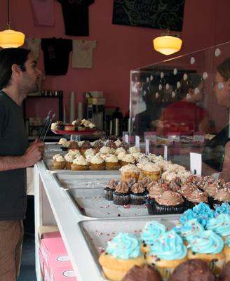 a man looking at a display of cupcakes