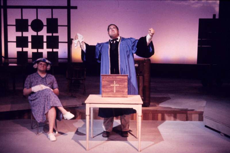 a man in a robe and hat standing on a stage