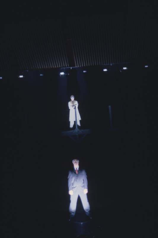 a man standing in a suit and a woman standing in a dark room