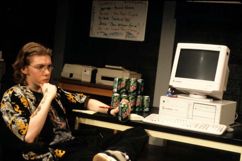 a man sitting at a desk with a computer and cans of beer