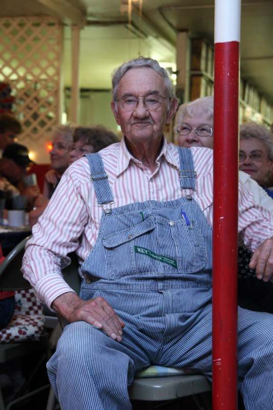 a man in overalls sitting in a chair