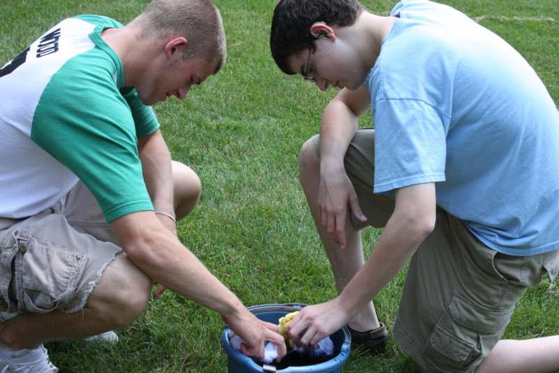 a couple of young men picking up something in a bucket