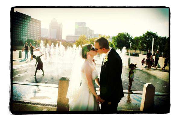 a man and woman kissing in front of a fountain