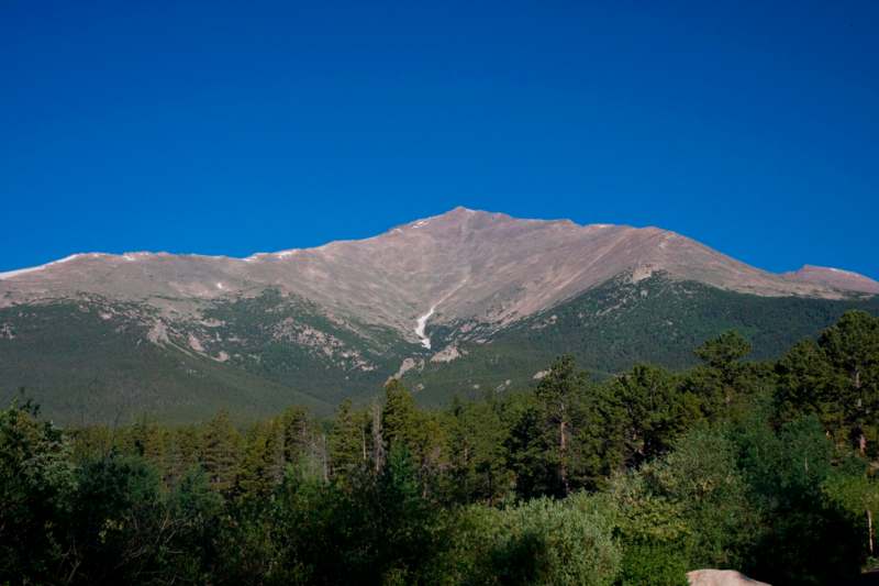 a mountain with trees and blue sky