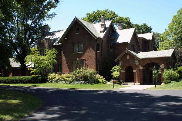 a large brick house with trees and a driveway
