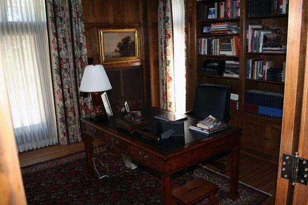 a desk in a room with bookshelves and a lamp