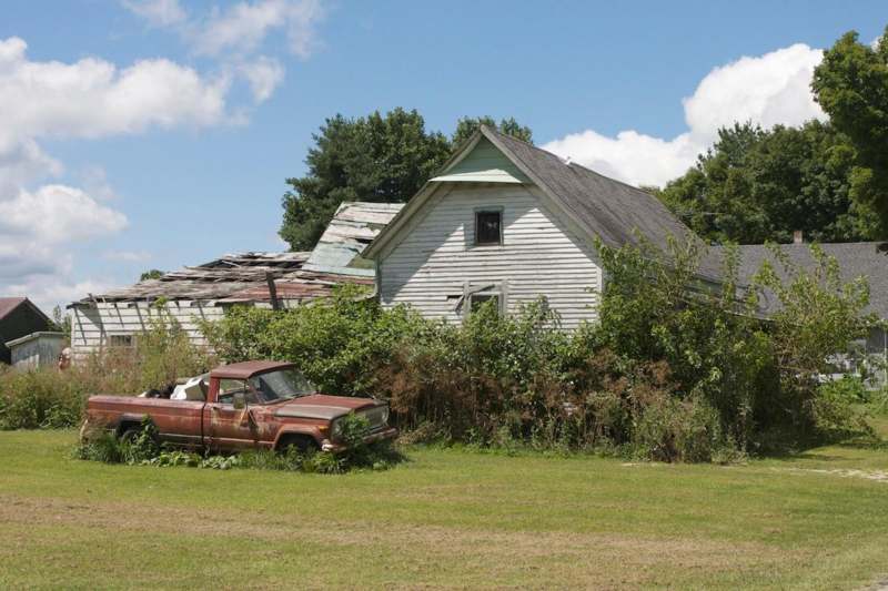 a old car in a field next to a house