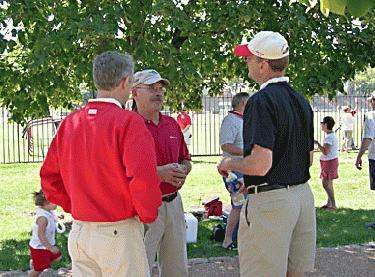 men in red shirts and khakis talking to a group of people