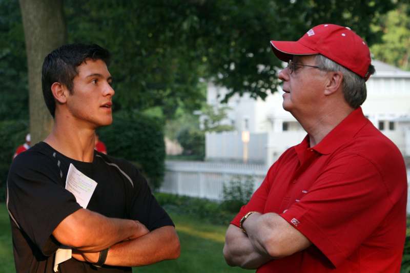 a man in red shirt and red cap standing next to a young man in red shirt