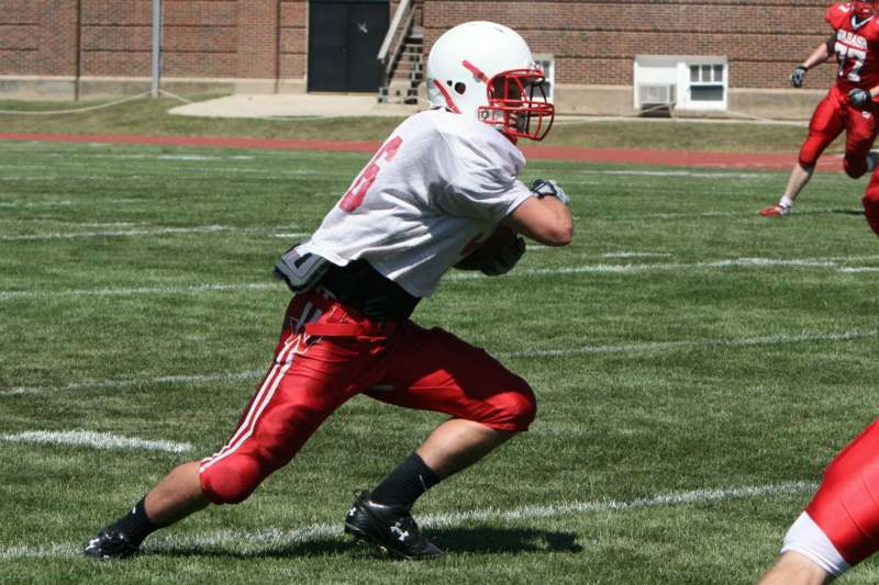 a football player in a white jersey and red shorts holding a football