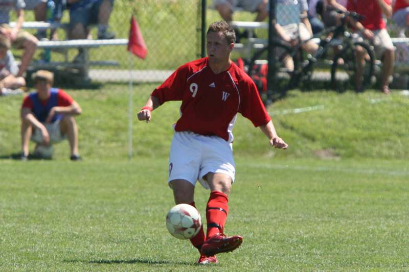a man in a red shirt kicking a football ball