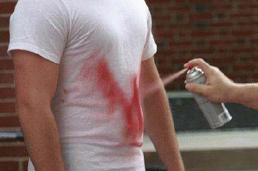 a person spraying red paint on his shirt