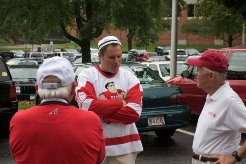 a man in a red and white jersey talking to a group of men