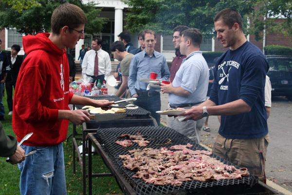 a group of men cooking meat on a grill