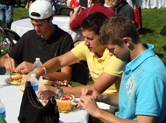 a group of young men eating at a picnic table