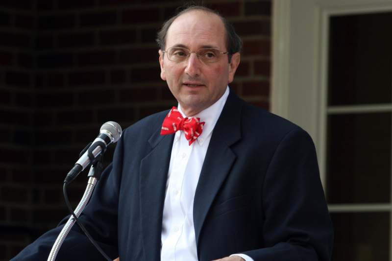 a man in a suit and bow tie speaking into a microphone