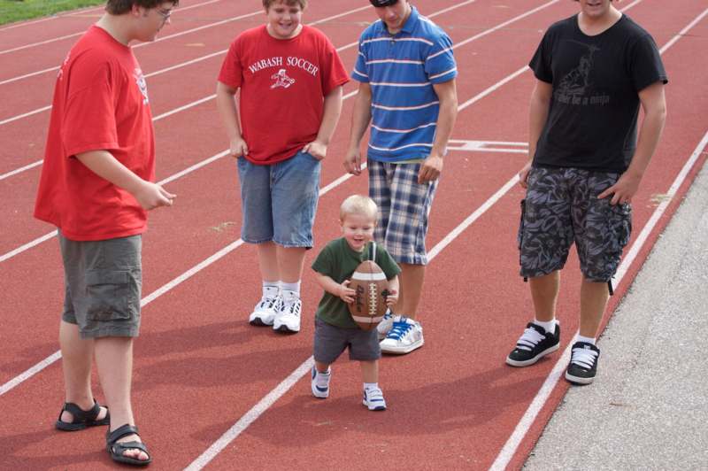 a group of boys standing on a track with a small boy holding a football