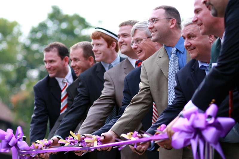 a group of men in suits holding a ribbon