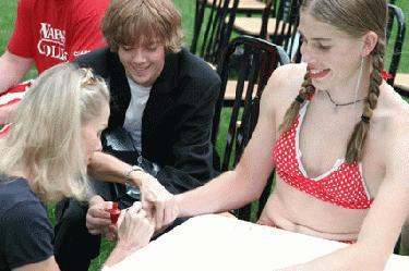 a woman in a swimsuit painting a woman's nails