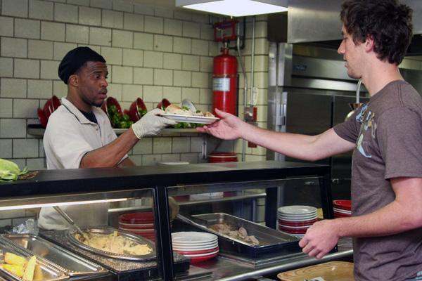 a man handing a plate of food to a man