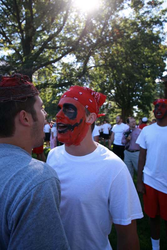 a man with red face paint talking to another man
