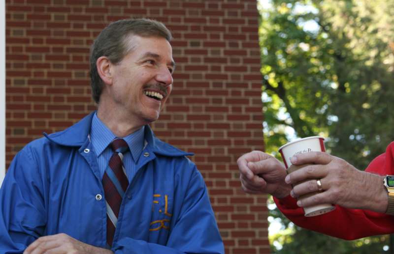 a man smiling and holding a cup of coffee