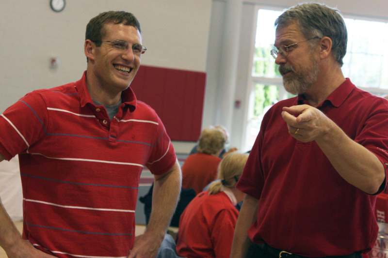 a man in red shirt talking to another man