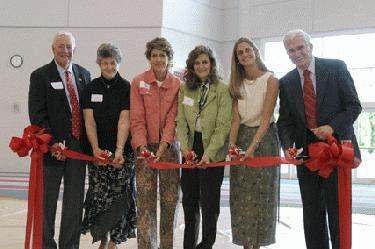 a group of people cutting a red ribbon