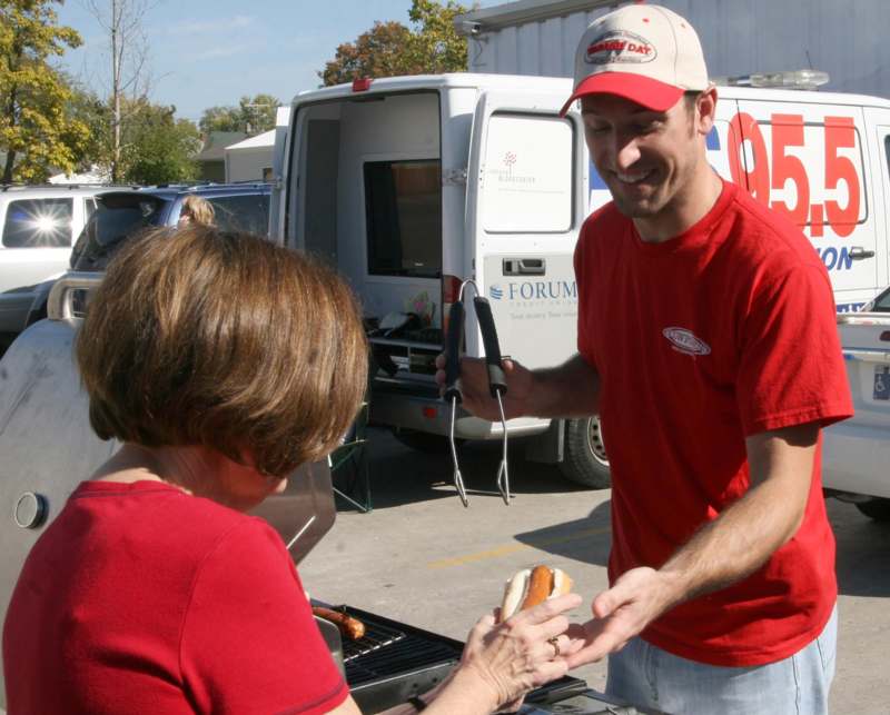 a man serving a hot dog to a woman