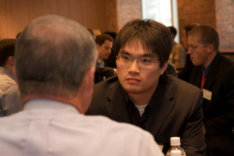 a man in a suit and glasses talking to another man