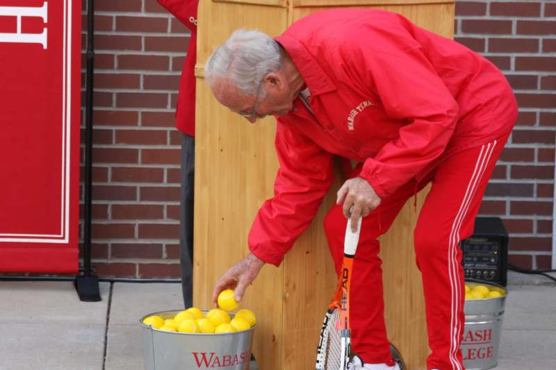 a man putting tennis balls in a bucket