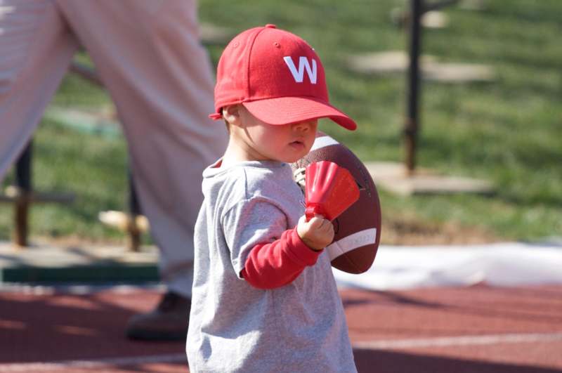 a child holding a football and a red hat