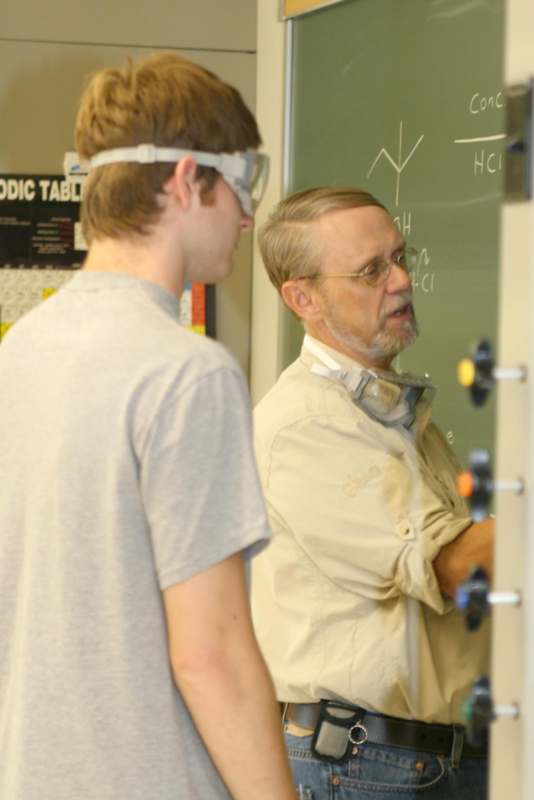 a man wearing safety goggles and standing next to a man wearing goggles