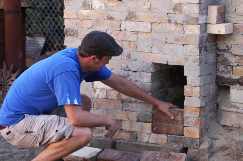 a man placing bricks in a brick chimney