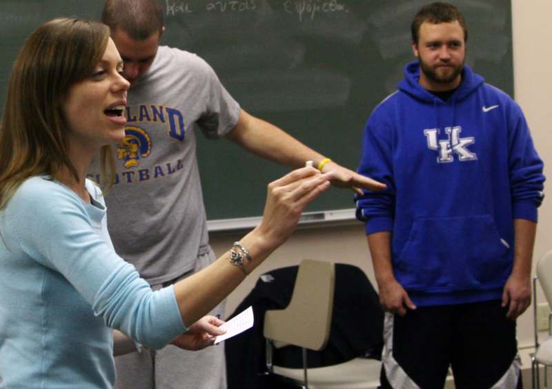 a woman pointing at a man in front of a chalkboard