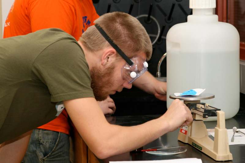 a man wearing goggles and looking at a microscope