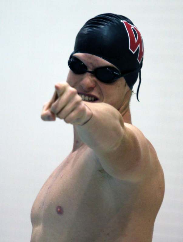 a man in a swim cap pointing at the camera