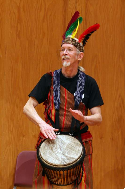 a man wearing a feather headdress and holding a drum